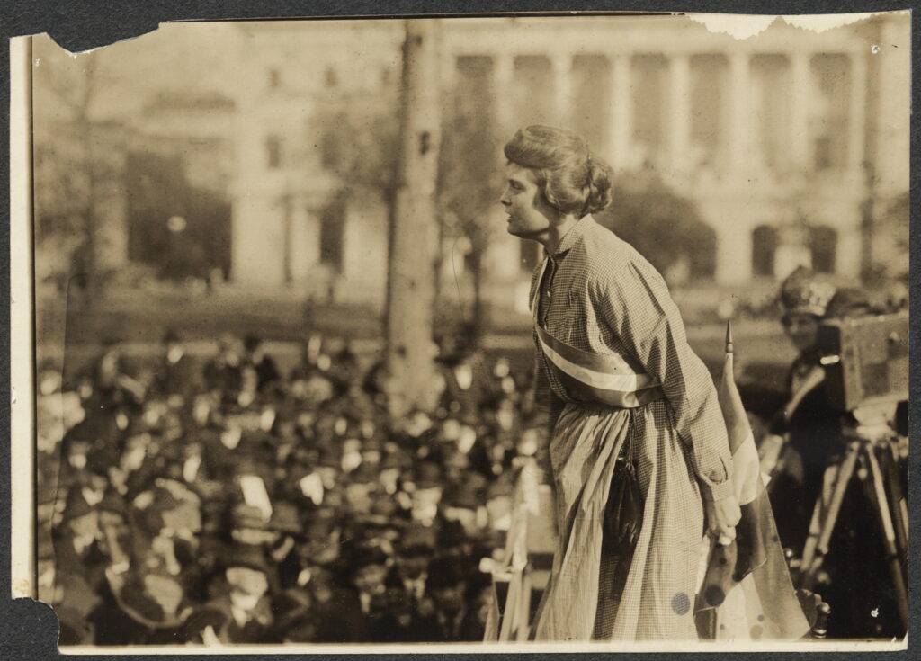 Lucy Branham dressed in replica prison garb and forcefully speaking to a crowd