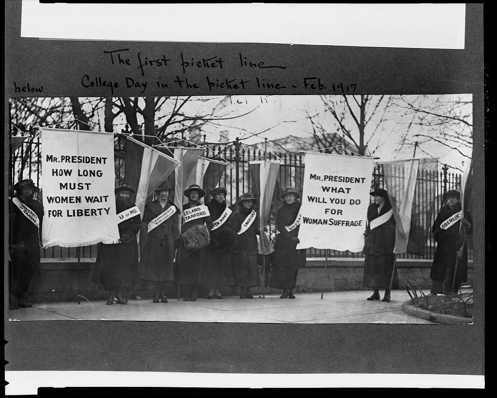 Suffragists carrying banners in front of White House, including the banner that says 