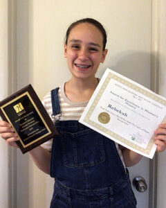 Rebeka holing two certificates and smiling 