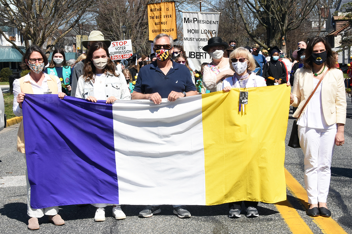 Four women and a man holding a suffrage flag