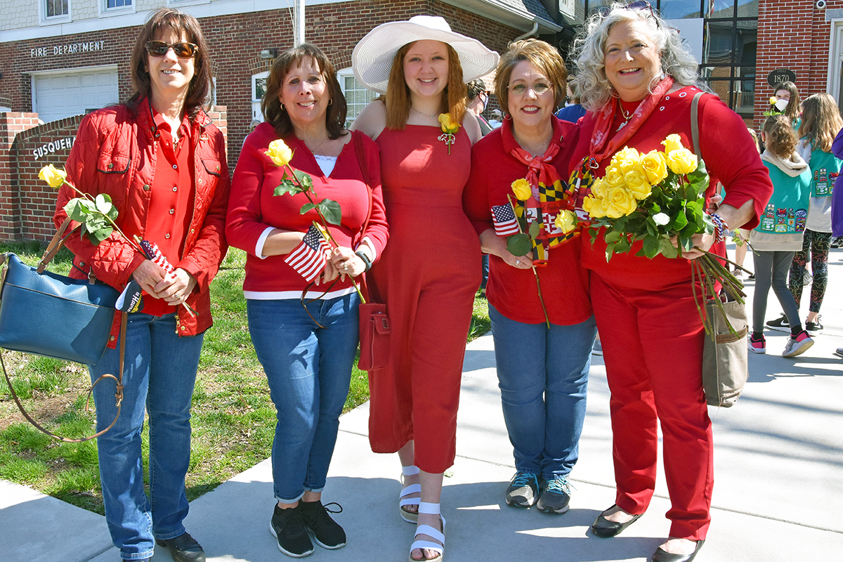 Five women from the local Republican chapter, dressed in red and carrying yellow roses