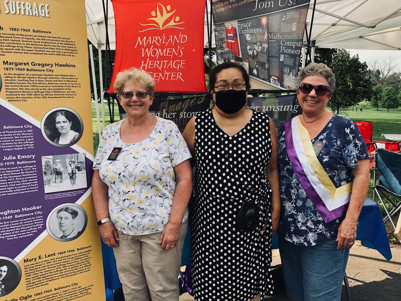 Bea Dane, Jean Thompson and Diana Bailey standing in front of displays in Druid Hill Park for Women's Equality Day