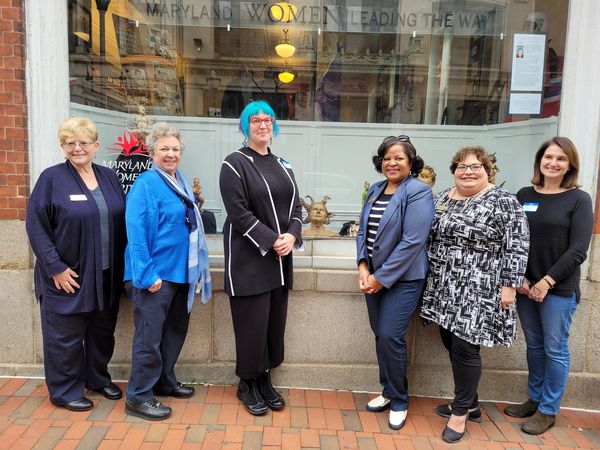 Five women standing at MWHC window that holds Megary's sculptures