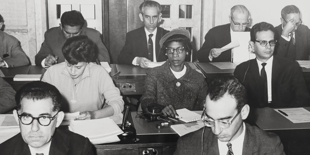 Phyliss Williams at a conference. She is th only Black person among half dozen white men seated. 