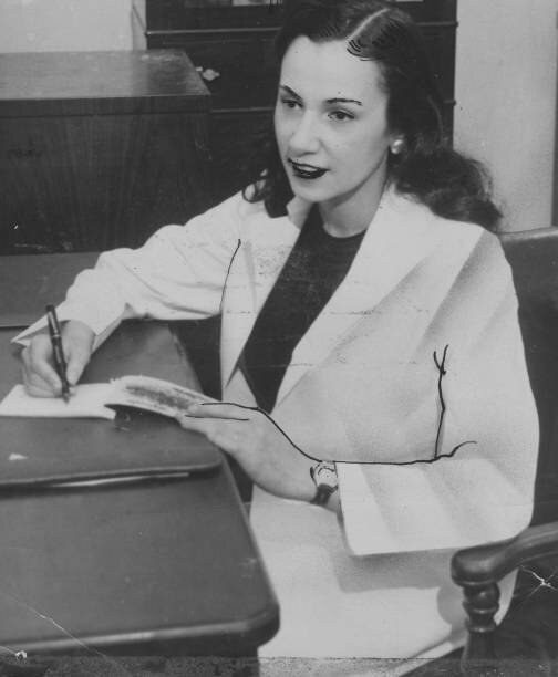 Balck and White Image of Dr. Young sitting at her desk, writing. She is wearing a white jacket