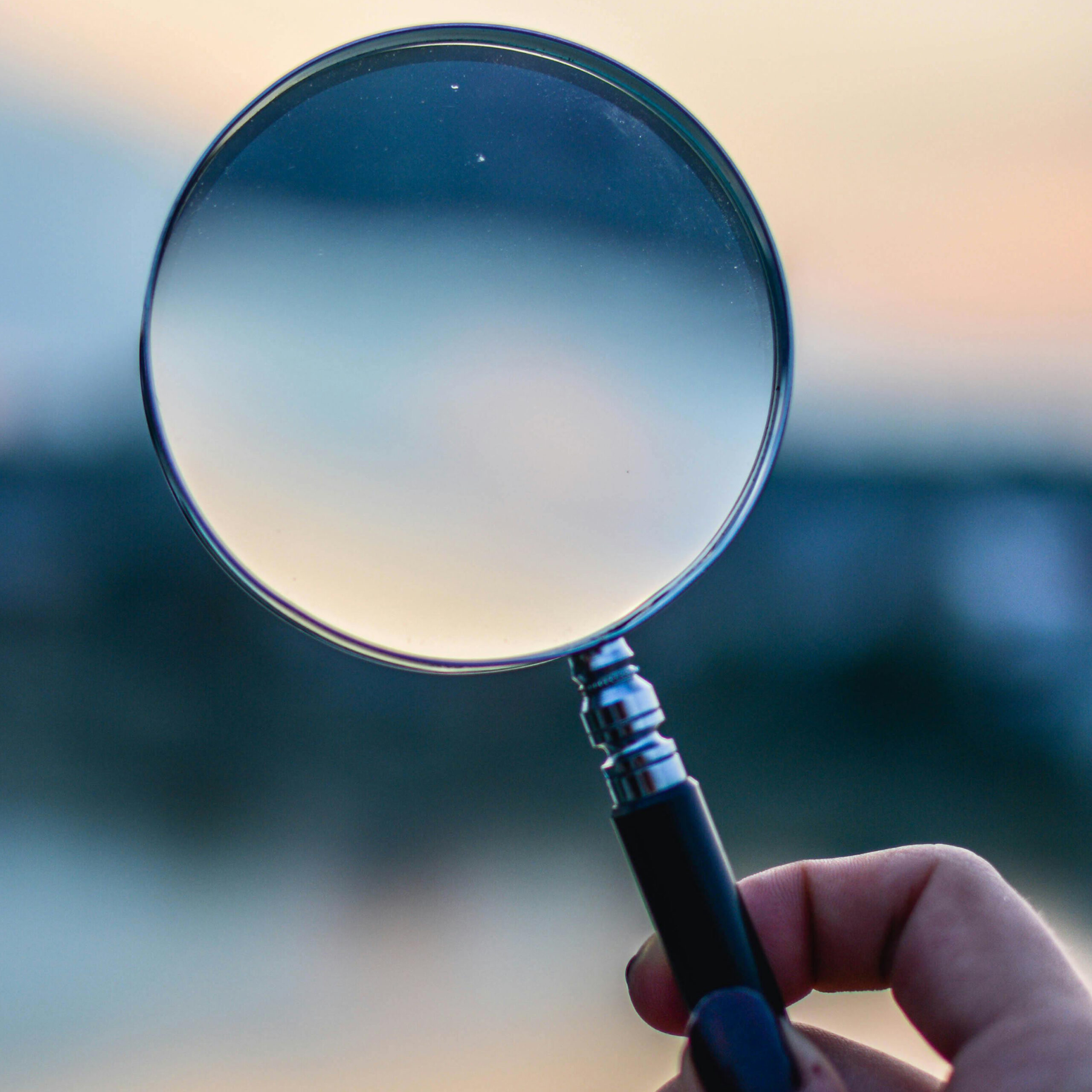 a hand holding a magnifying glass.