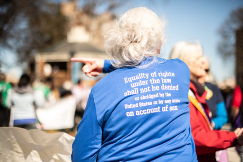 A woman with grey hair wearing a t shirt that spells out the amendment