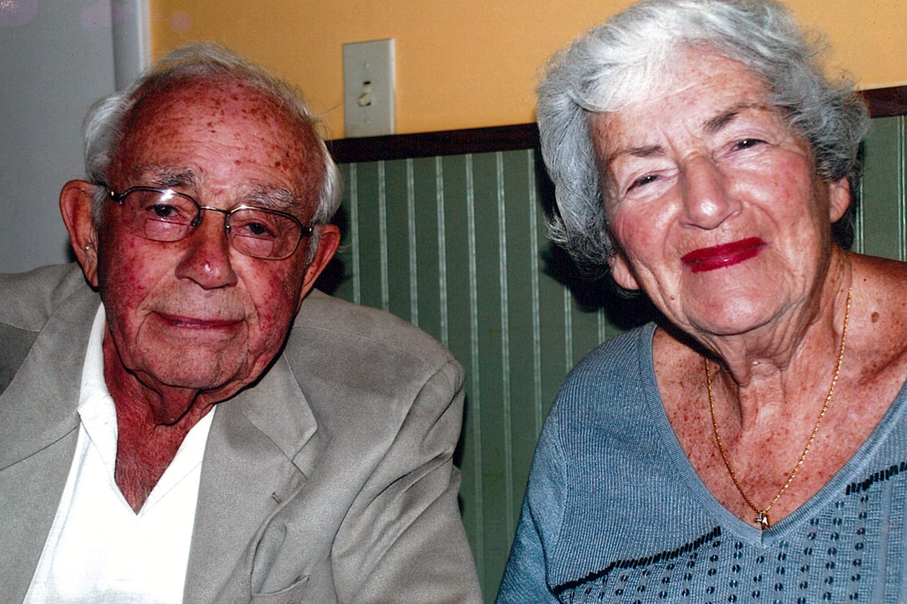 A photo of Arthur and Bernice Friedland. He is wearing a grey sport coat and she is wearing a blue blouse. They are about 75 - 80 years old in this photo.