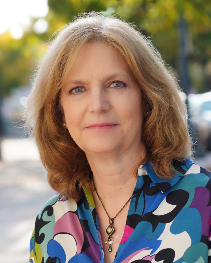 Anne Calmuci haș shoulder length blond hair and is wearing a print blouse