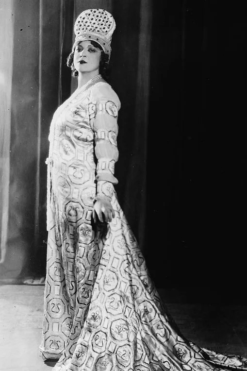 Ponselle wearing an evening gown with train and a crown on her head; full length photo