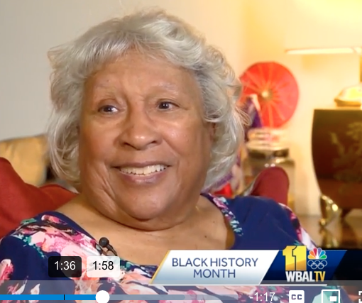 A screen shot of a WBAL TV interview with Helena Hicks. She is about 80 years old and wearing a blue print dress